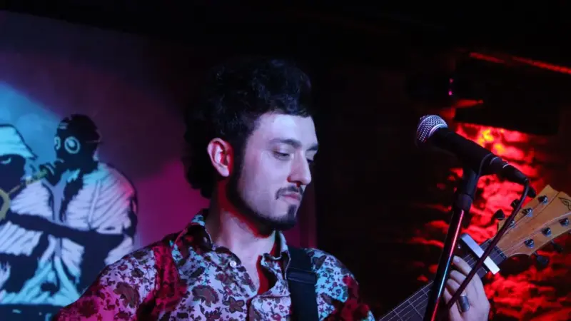 Mabel Matiz’in 2011’de Ankara’daki bir konserde çiçek desenli gömleğiyle akustik gitar çalarken mikrofona doğru eğildiği an