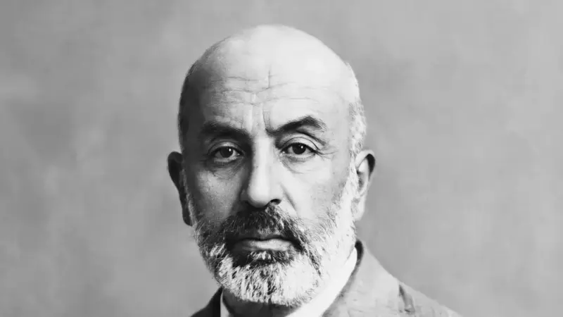 Mehmet Âkif Ersoy’un siyah beyaz portresi; kır sakallı, kel başlı şair ceketiyle kameraya bakıyor