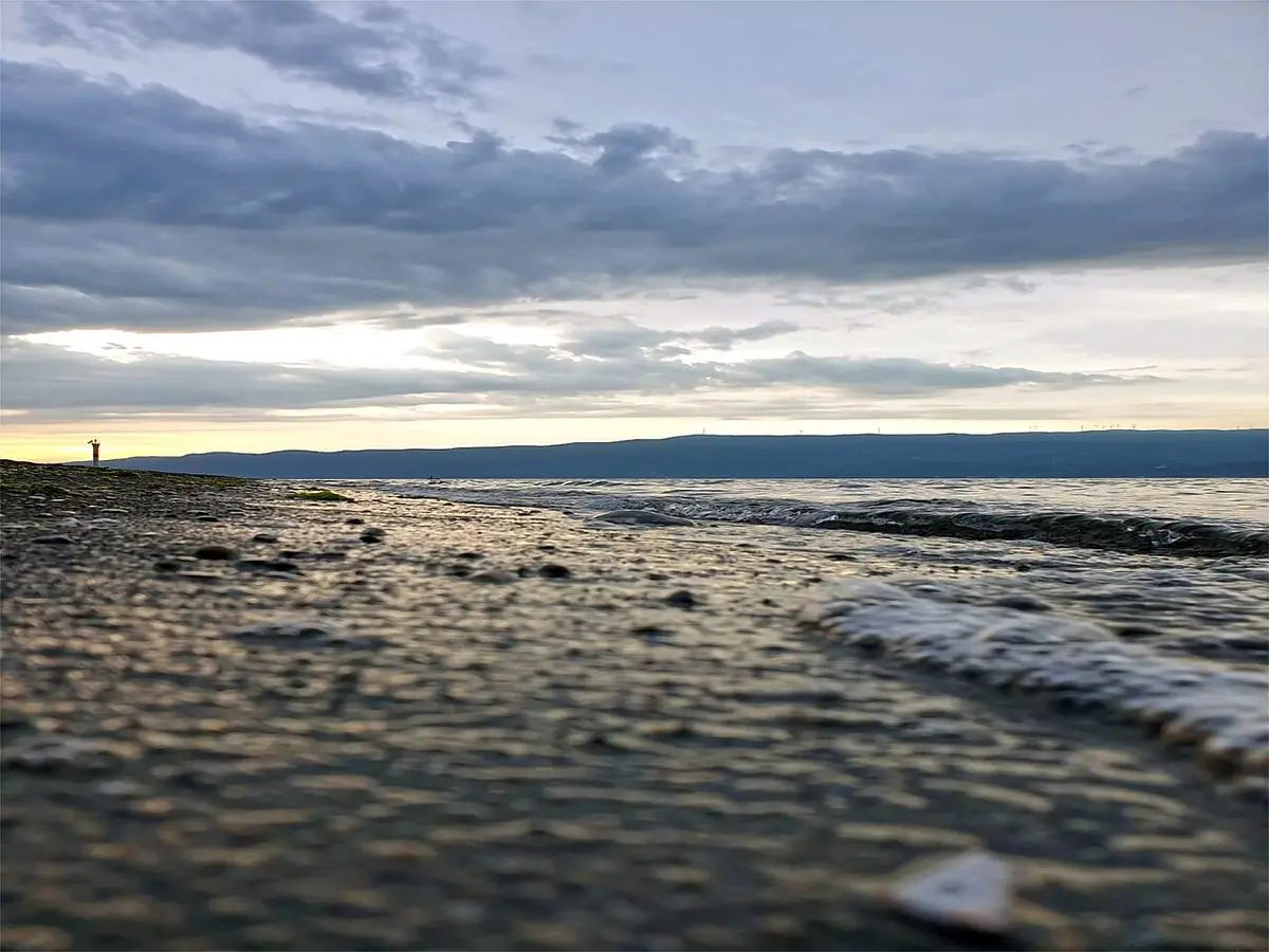 Gemlik sahilinde yağmur sonrası bulutlu gökyüzü altında gün batımı ve kıyıya vuran dalgalar