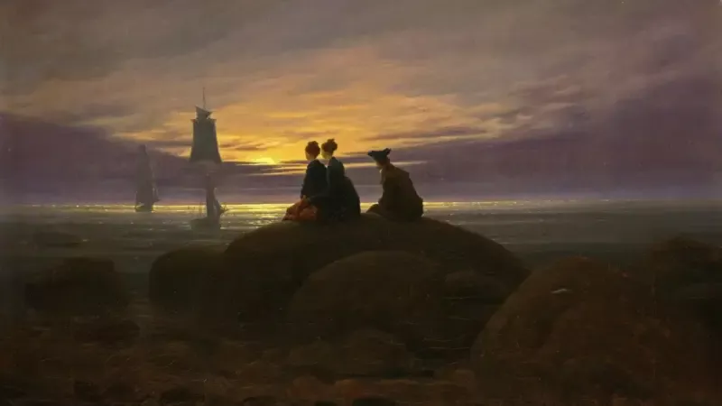 Caspar David Friedrich'in Denizde Ay Doğuşu tablosu: alacakaranlıkta deniz kıyısındaki büyük bir kayanın üzerinde oturan iki kadın ve bir erkeğin, ay doğarken kıyıya yaklaşan iki yelkenliye sırtları dönük bakışı