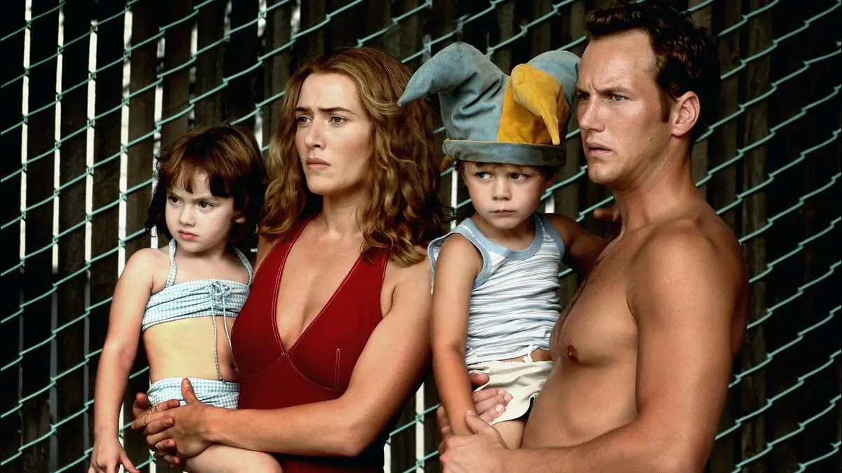 Tutku Oyunları (Little Children) filminin tanıtım görselinde tel örgü önünde iki çocukla birlikte duran Sarah rolündeki Kate Winslet ve Brad rolündeki Patrick Wilson
