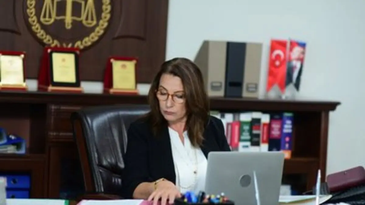 Aldatmak dizisinden, arkasında adalet terazisi amblemi ve Türk bayrağı bulunan makam odasında dizüstü bilgisayarının başında oturan hakim Güzide rolündeki Vahide Perçin