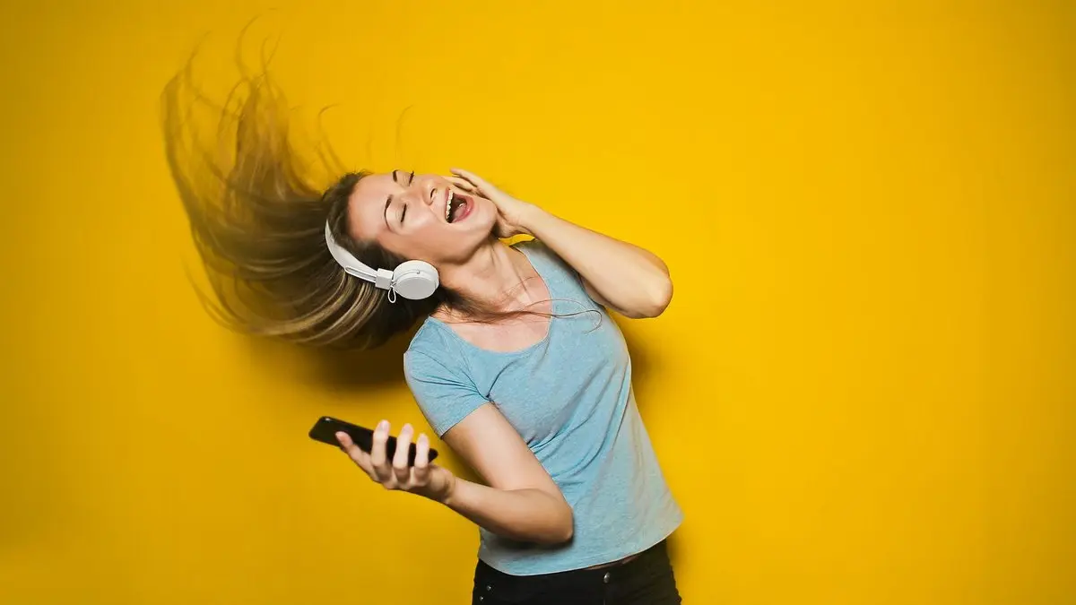 Kulaklıkla müzik dinlerken şarkıya eşlik eden genç bir kadın