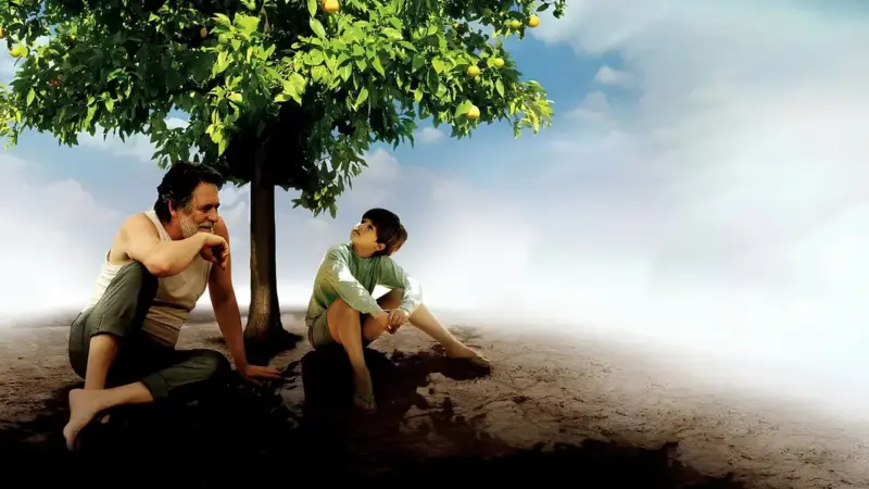 Şeker Portakalı’nın 2012 tarihli film uyarlamasından sahne: Portuga ile Zezé, dalları portakal dolu bir ağacın altında yan yana oturmuş konuşuyor