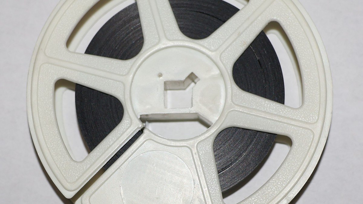 Üzerine siyah film şeridi sarılmış beyaz plastik bir 16 mm film makarası
