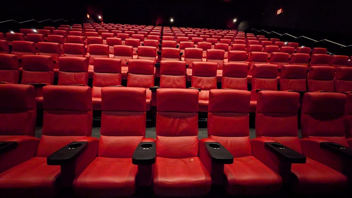 Karanlık bir sinema salonunda sıra sıra dizilmiş boş kırmızı koltuklar