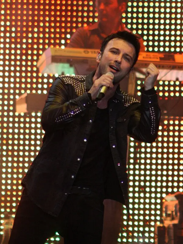 Tarkan’ın 2011’de siyah ceketiyle, arkasında ışıklı sahne panoları varken mikrofonla şarkı söylediği konser fotoğrafı