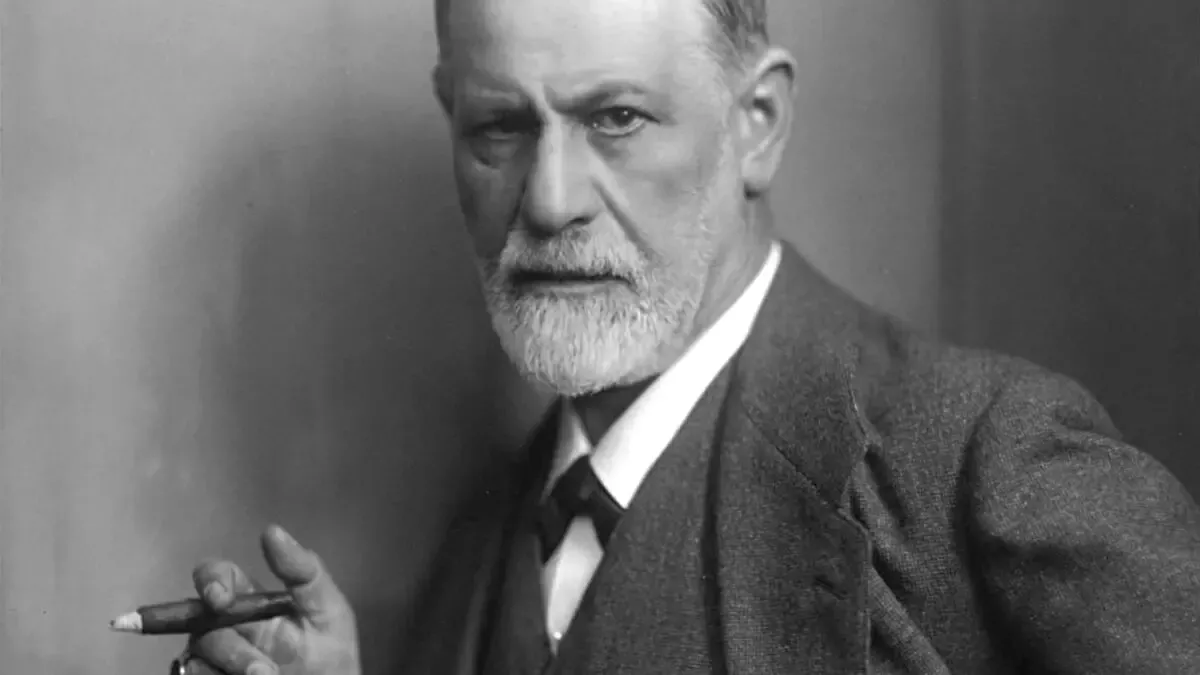 Sigmund Freud'un koyu takım elbise, yelek ve papyonla, sağ elinde bir puro tutarak kameraya ciddi bir ifadeyle baktığı siyah-beyaz portresi