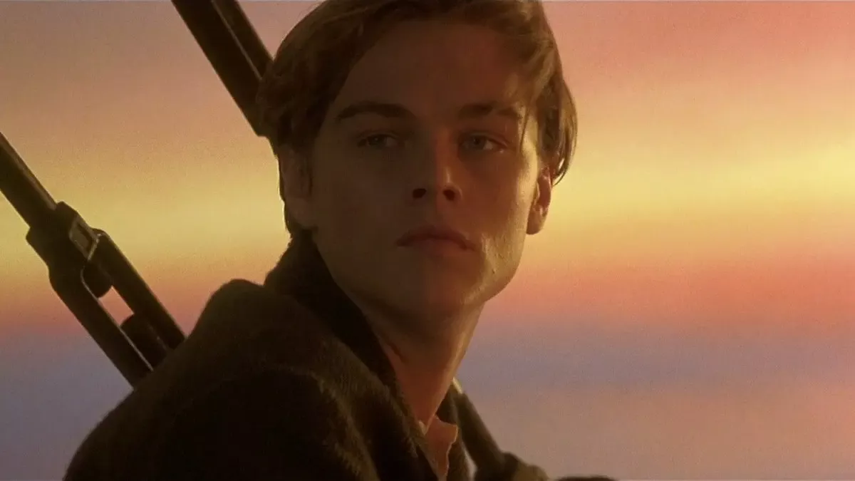 Titanic filminden sahne: turuncu gün batımı gökyüzü önünde, geminin pruvasında ciddi bakışlarla duran Jack Dawson rolündeki Leonardo DiCaprio