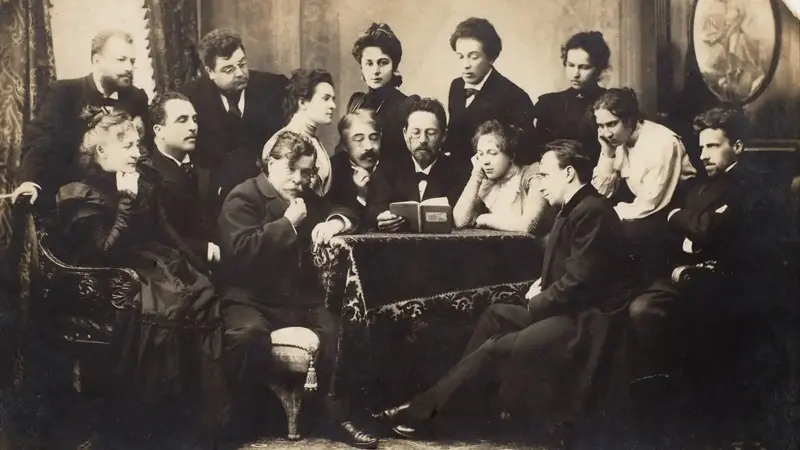 Anton Çehov'un bir masanın başında oturup elindeki kitaptan Martı'yı okuduğu, çevresinde Stanislavski ve Moskova Sanat Tiyatrosu oyuncularının onu dinlediği sepya tonlu toplu fotoğraf