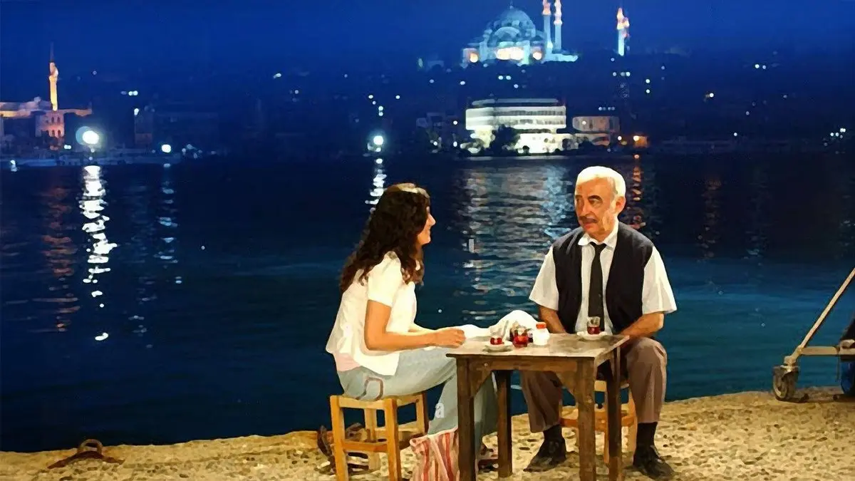 Gönül Yarası filminden, gece İstanbul Boğazı kıyısında bir masada oturan genç bir kadın ile yaşlıca bir adam