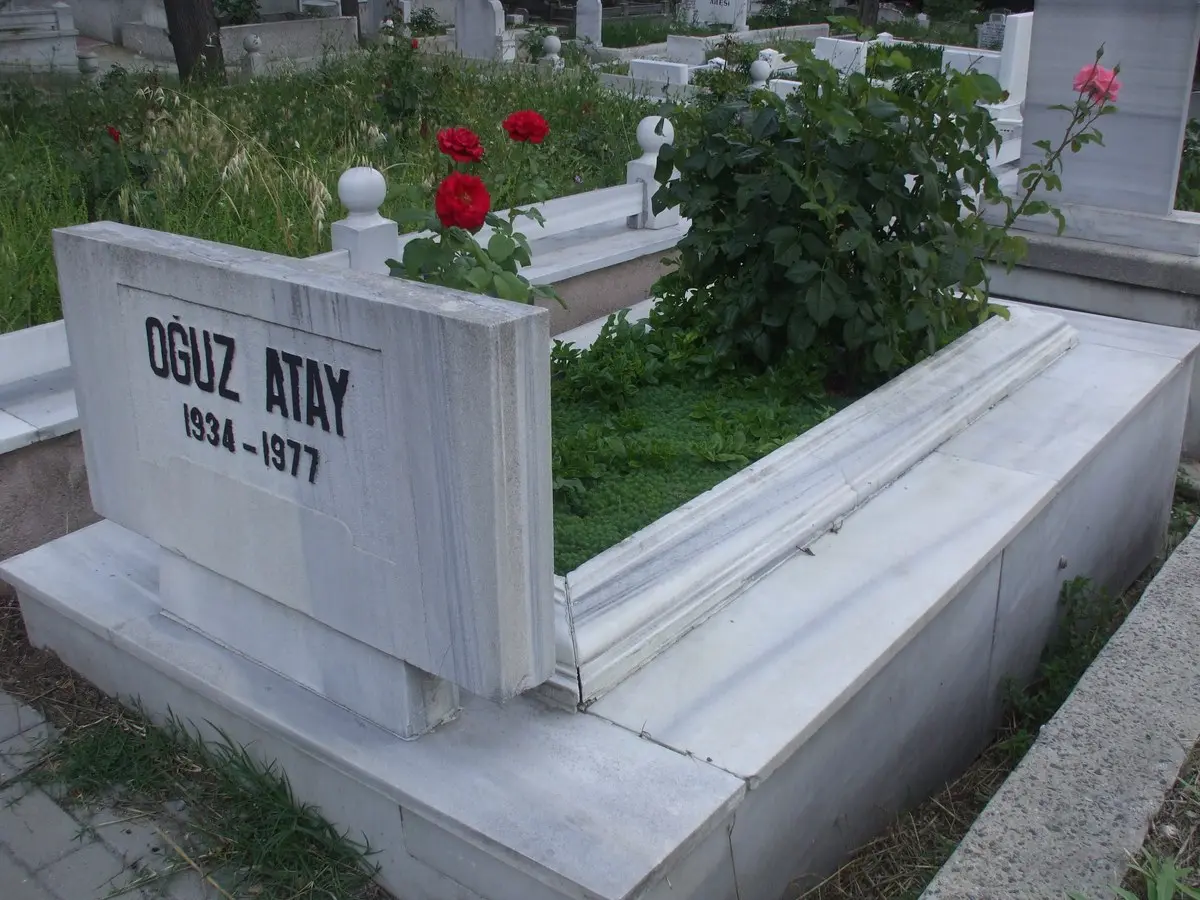 Edirnekapı’daki mezarlıkta, üzerinde Oğuz Atay 1934-1977 yazan beyaz mermer mezar taşı ve arkasında güller