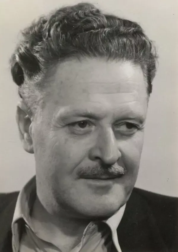 Nâzım Hikmet'in kıvırcık kır saçları, bıyığı ve yakası açık gömleğiyle yana doğru baktığı siyah-beyaz portre fotoğrafı