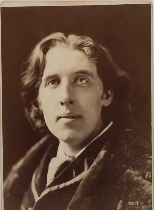 Uzun dalgalı saçlı genç Oscar Wilde'ın kürk yakalı paltosuyla başını hafifçe yukarı kaldırıp uzağa baktığı sepya tonlu fotoğrafı
