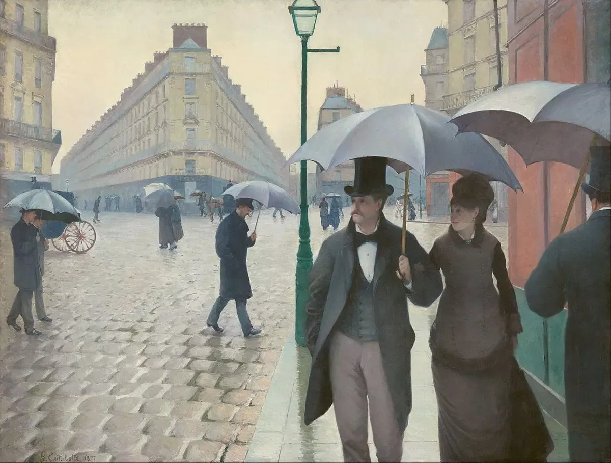Caillebotte’nin Paris Sokağı, Yağmurlu Gün tablosu: Islak, parlak Arnavut kaldırımlı geniş bir Paris kavşağında şemsiyeleriyle yürüyen şık giyimli bir çift ve arka planda şemsiyeli yayalar, ortada bir sokak lambası