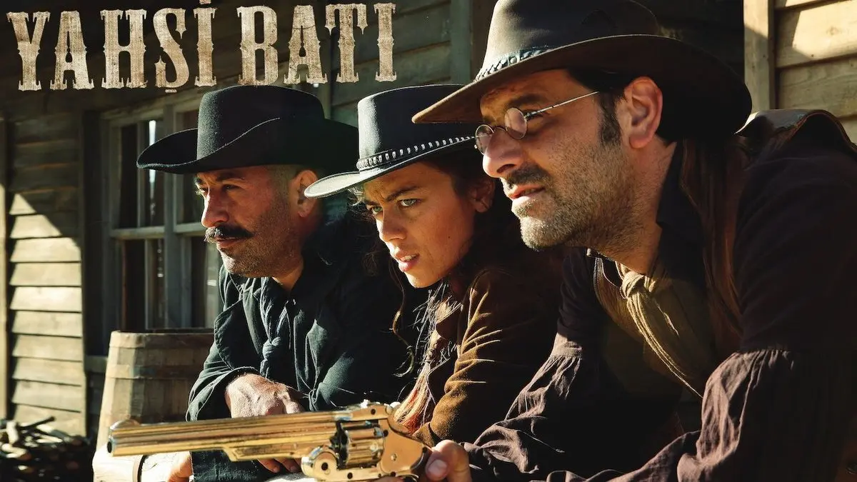 Yahşi Batı filminden tanıtım karesi: ahşap bir binanın verandasında siyah şapkalı Aziz Vefa, kovboy şapkalı genç bir kadın ve gözlüklü Lemi Galip yan yana eğilmiş, önlerinde altın renkli bir tüfek; sol üstte Yahşi Batı yazısı