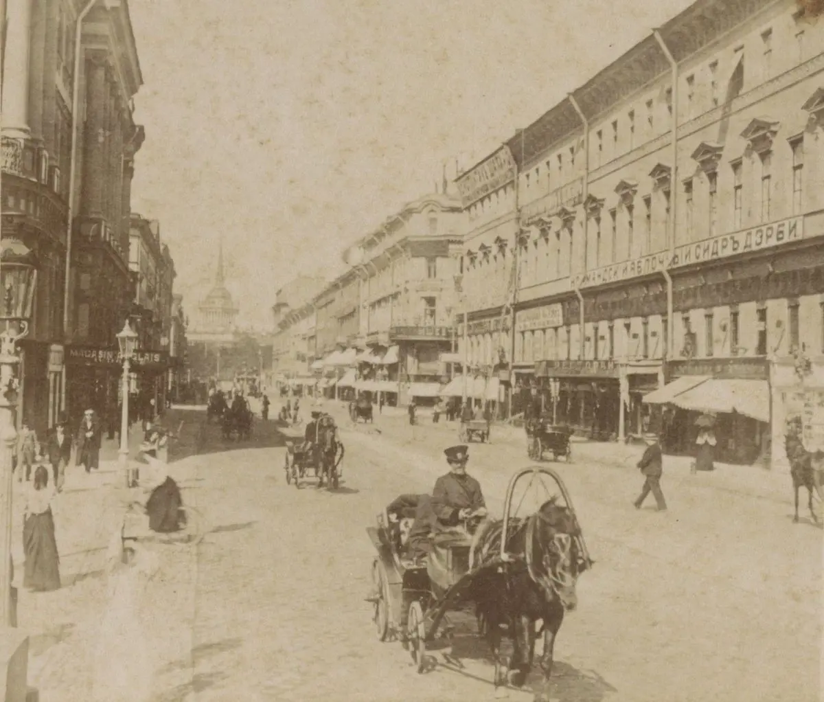19. yüzyılın ikinci yarısından sepya tonlu fotoğrafta Petersburg’daki Nevski Prospekti; önde tek atlı bir arabada oturan arabacı, kaldırımlarda yürüyen insanlar, tabelalı dükkânlar ve uzakta Amirallik binasının kulesi
