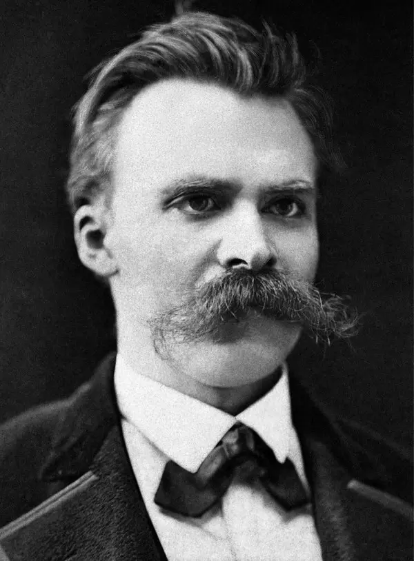 Gür bıyıklı ve geriye taranmış saçlı Friedrich Nietzsche'nin ceket ve papyonla yana doğru baktığı siyah-beyaz portre fotoğrafı