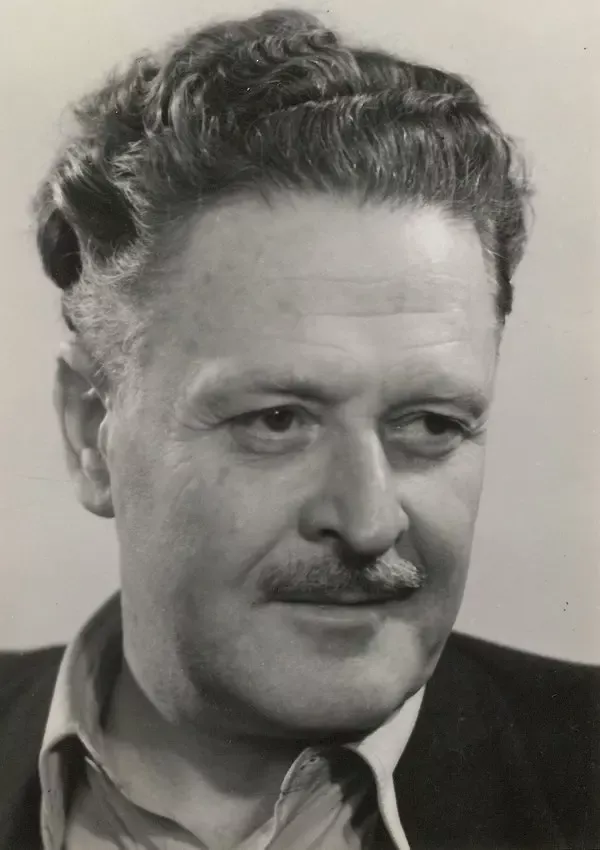 Nâzım Hikmet'in kıvırcık kır saçları, bıyığı ve yakası açık gömleğiyle yana doğru baktığı siyah-beyaz portre fotoğrafı
